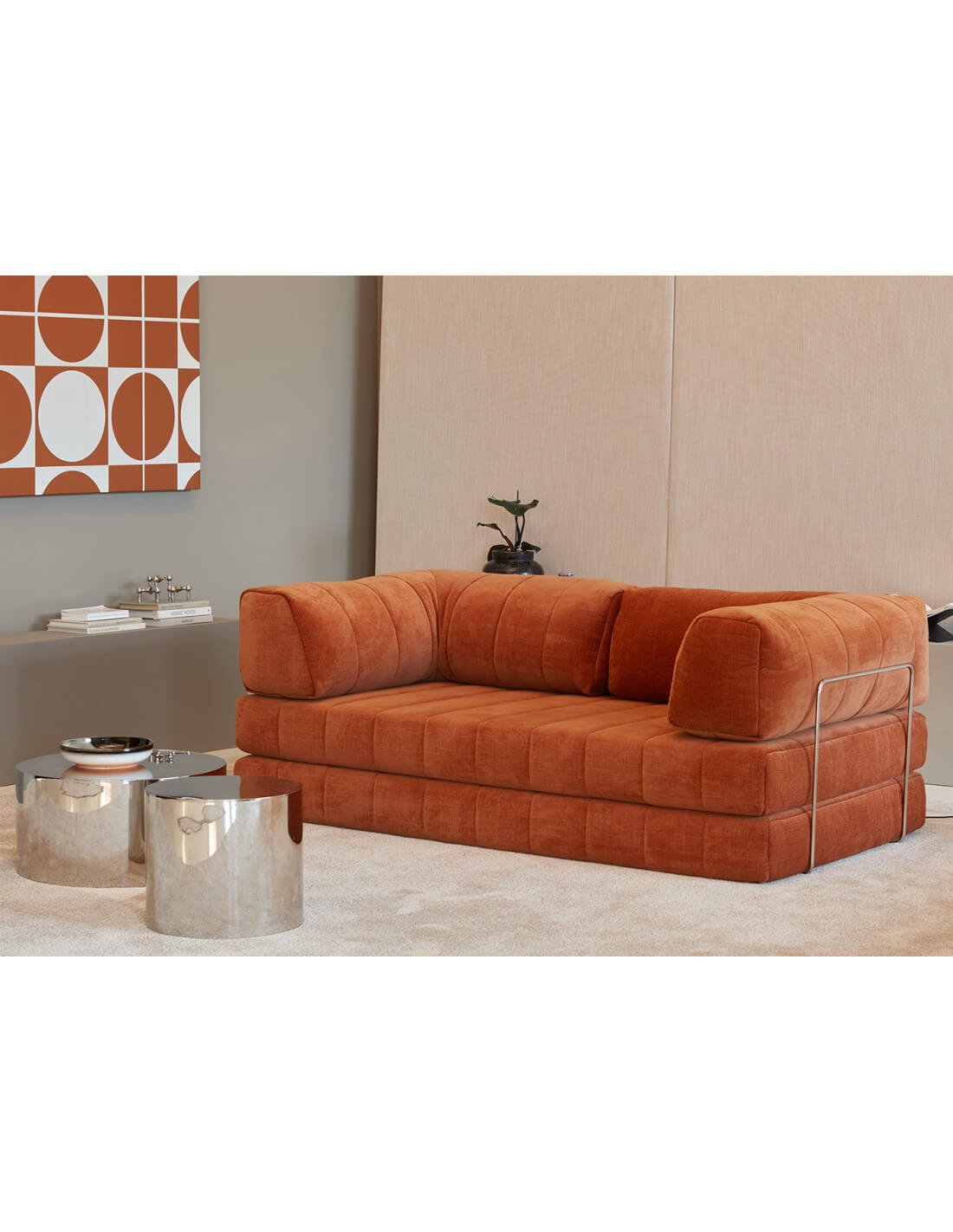 canapé modulable orange en velours dans un salon moderne, avec tables basses métalliques et décoration géométrique murale au style design.