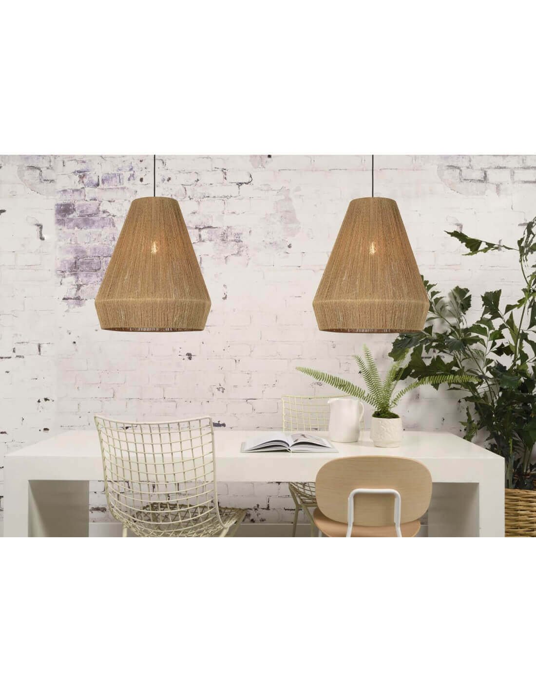 Lumières suspendues en rotin au-dessus d’une table blanche, décor minimaliste avec plantes et chaises en métal et bois.