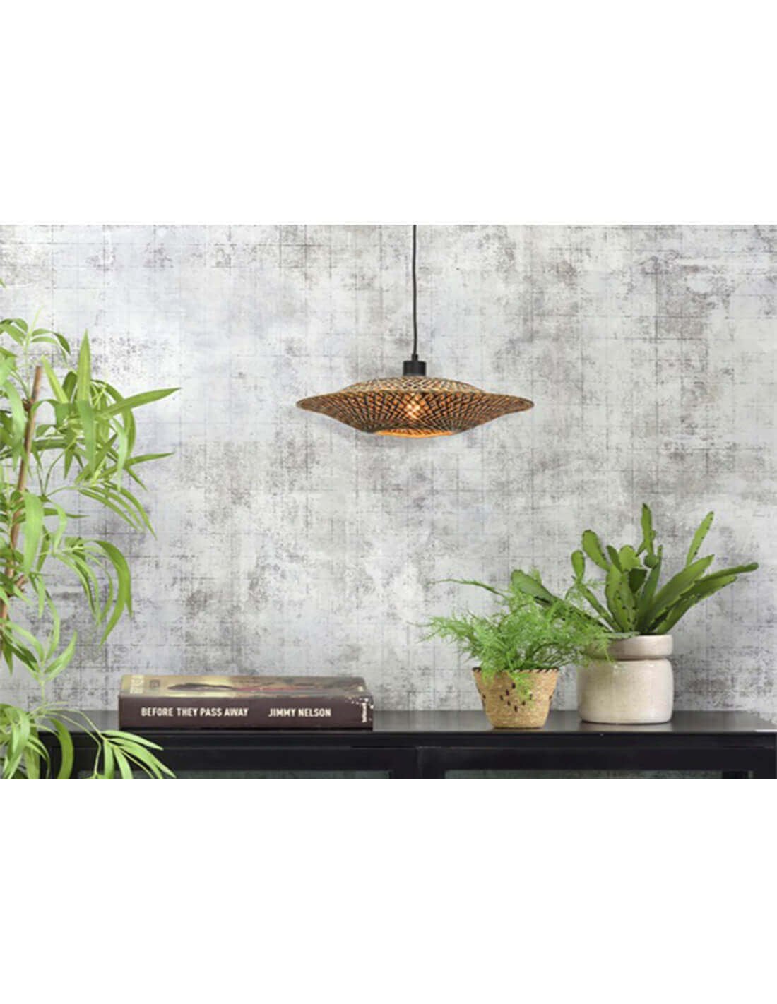 Luminaires suspendus en rotin au-dessus d’un plan de travail, entouré de plantes vertes et de livres décoratifs.