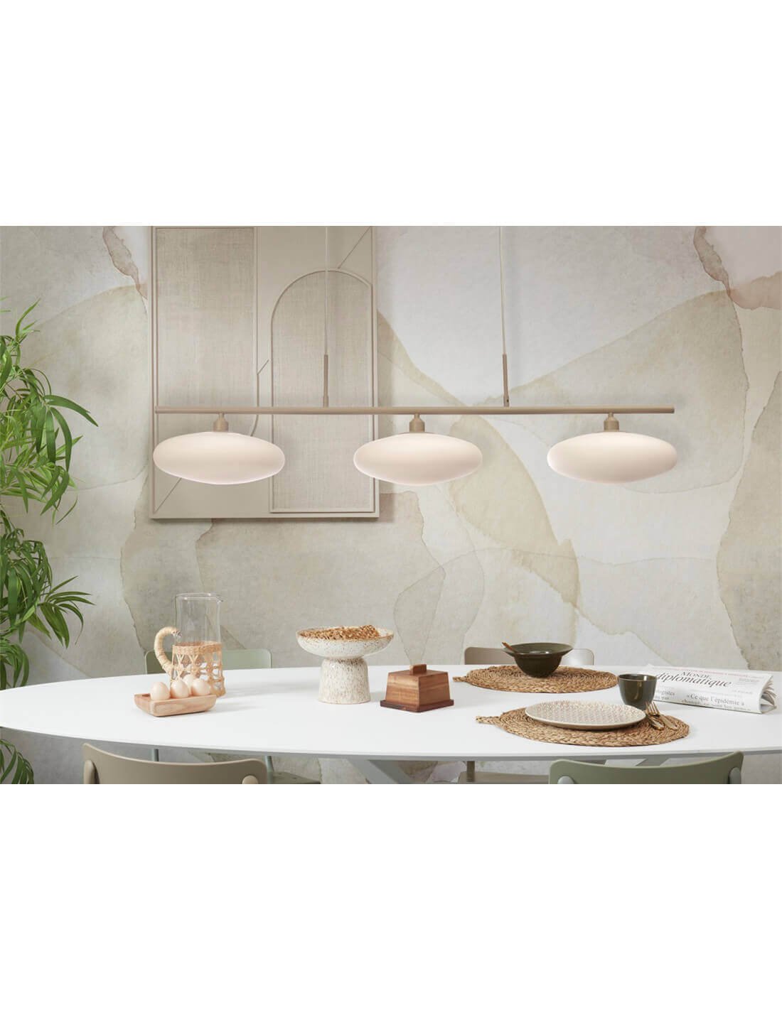 Lustre contemporain à trois abat-jours blancs au-dessus d’une table ronde blanche en salle à manger, décor minimaliste et mur décoratif pastel.